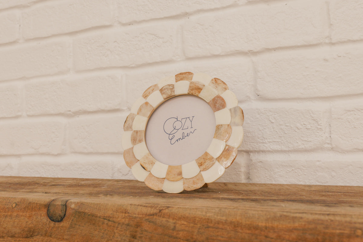 Decorative circular frame with 'Cozy Ember' text on a wooden surface and white brick wall background