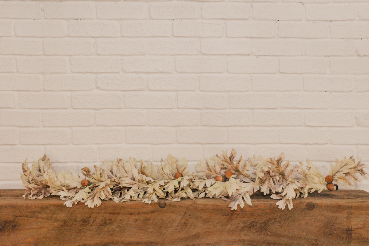 Decorative beige garland on a wooden surface with a white brick wall background
