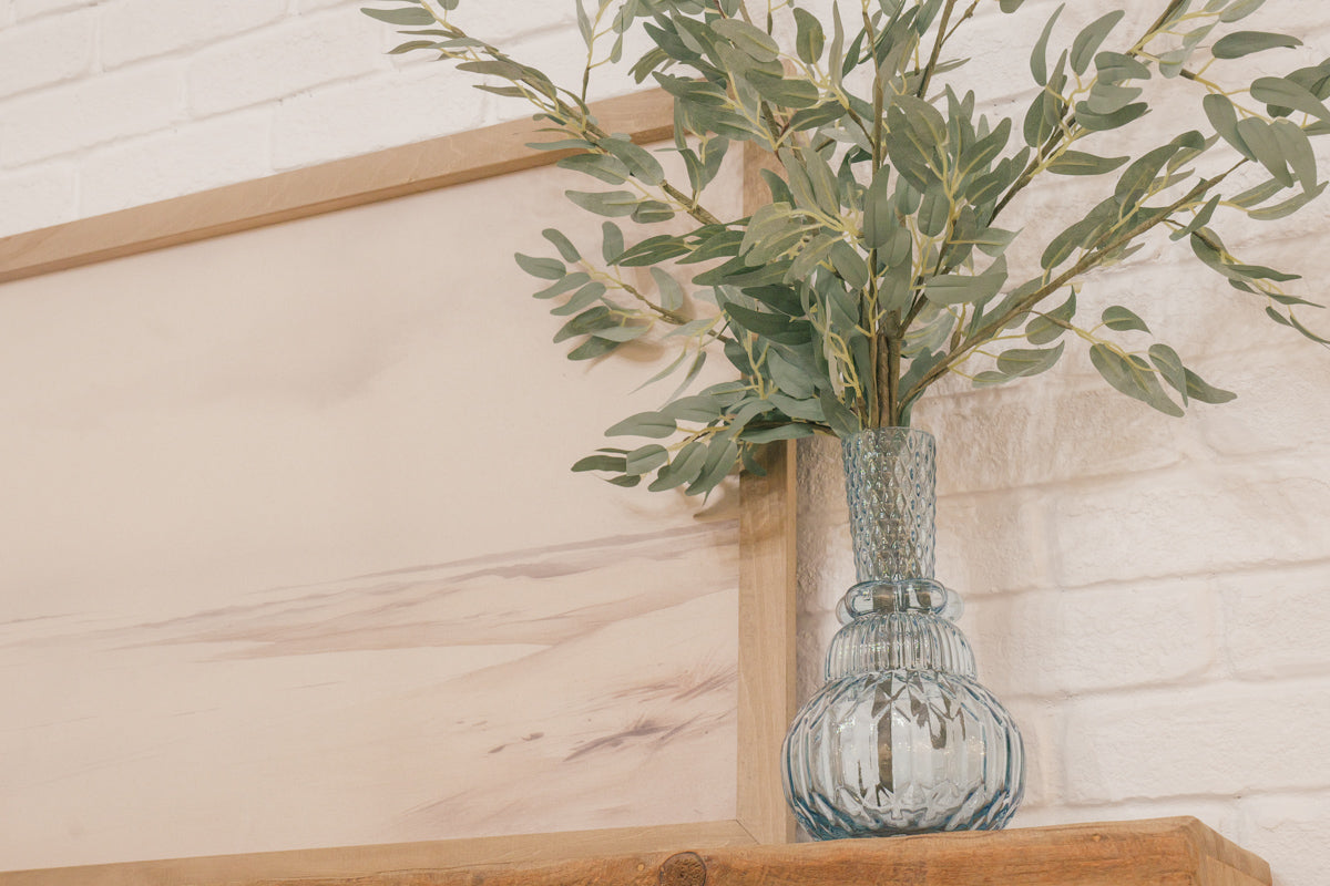 Close-up of Cozy Bundle mantel décor with flameless candles, hollow book, and vase with greenery inserts