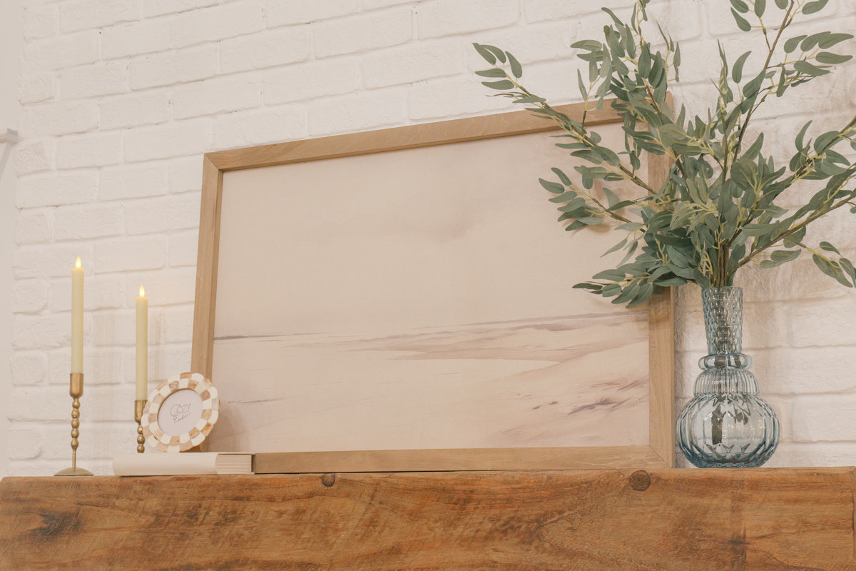 Close-up of Cozy Bundle mantel décor with flameless candles, hollow book, and vase with greenery inserts